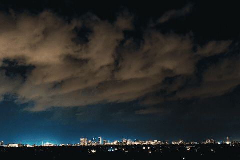 Animated loop: purple lightning flashing inside a dark shelf cloud over the lit Winnipeg skyline at night.